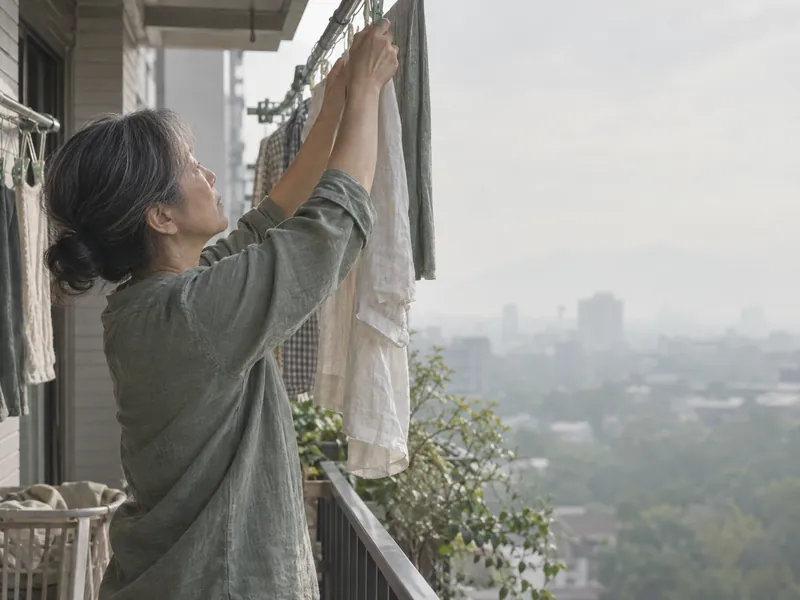 婦人在陽台把衣服掛上晾衣桿